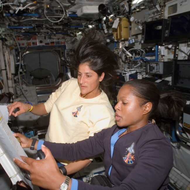 Two woman astronauts in space working